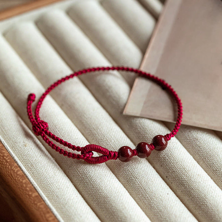 Buddha Stones Handgemaakte Armband van gevlochten touw met cinnaberkralen en een kalmerend effect. - Donkerrood touw (Polsomtrek 16-18 cm) - image 0